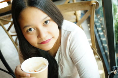 Portrait of young woman holding coffee cup in restaurant