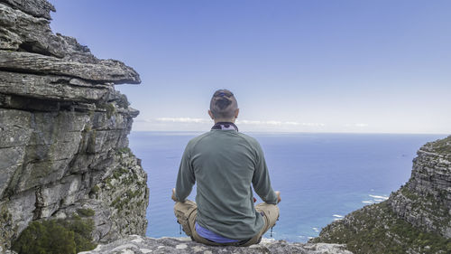 Rear view of man looking at sea against sky