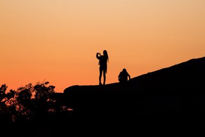 Silhouette people photographing against sky during sunset