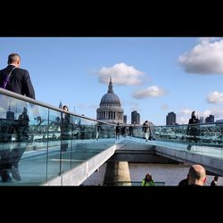 Tourists in front of building against cloudy sky