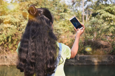 Rear view of woman photographing with mobile phone