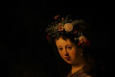 Portrait of woman with red flowers against black background