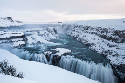 Scenic view of waterfall against sky during winter