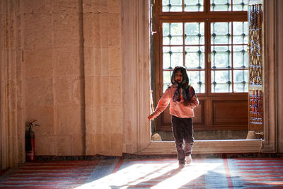 Portrait of woman standing against window