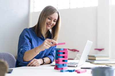 Young woman using mobile phone while sitting on table