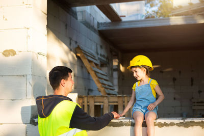 Rear view of father with daughter at construction site