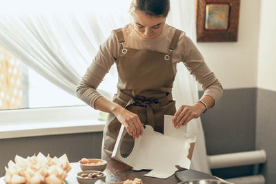 Woman bakery shop owner holding delivery box for customer order. cake in  kitchen. food delivery