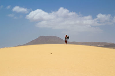 Rear view of man walking on sand dune in desert