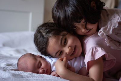 Side view pyramid of three children in pink lying on each other