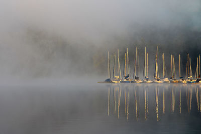 Wooden posts in lake against sky