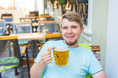 Portrait of smiling young man drinking glass at restaurant