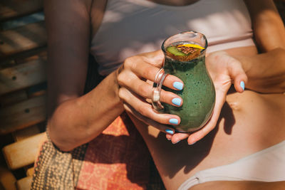 Midsection of woman holding drink in container