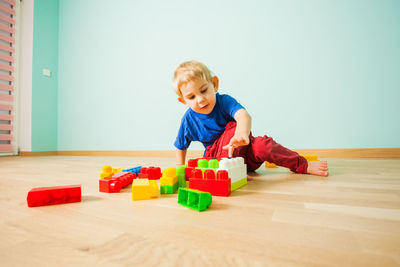 Cute boy with toy toys on floor at home