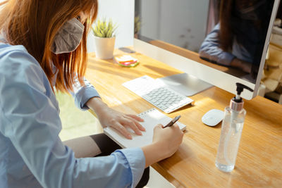 High angle view of woman using mobile phone while sitting on table