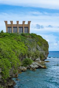 Built structure on rocks by sea against sky