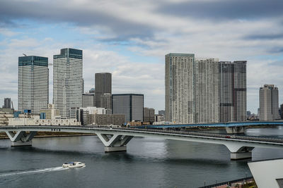 Bridge over river by buildings against sky in city