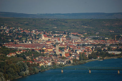 Aerial view of townscape by river against sky