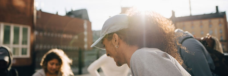 Close-up of smiling young man having fun with friends in city during sunny day