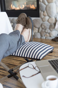 Low section of man resting legs on chair