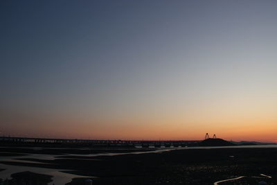 Scenic view of beach against clear sky during sunset