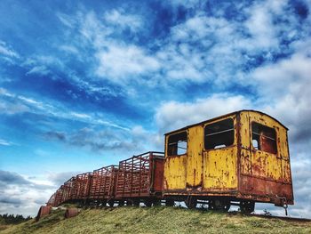 Low angle view of abandoned train on field against sky