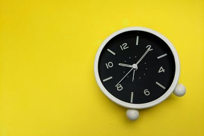 Close-up of clock on yellow wall