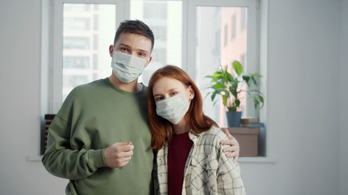 Portrait of young couple standing against wall