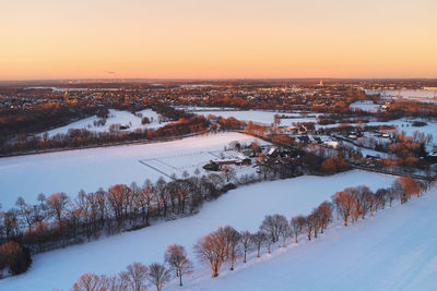 Snow covered agricultural landscape and small towns in industrial area during sunset in the winter