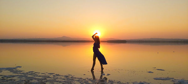 Man standing on beach against sky during sunset