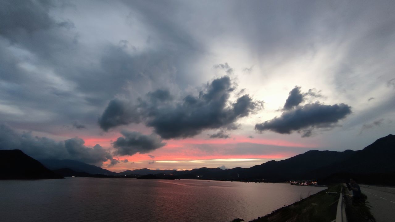 SCENIC VIEW OF SEA BY SILHOUETTE MOUNTAINS AGAINST SKY