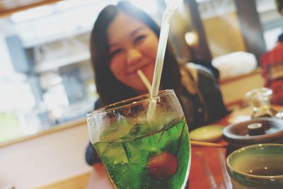 Close-up of young woman with drink on table