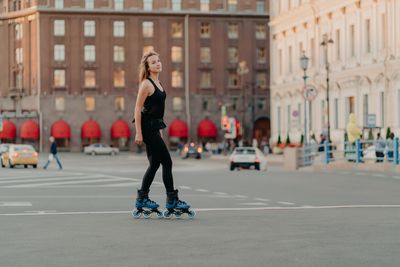 Full length of woman skateboarding on city street