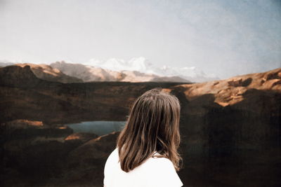 Rear view of woman standing on mountain against sky