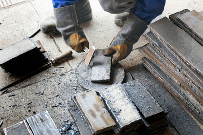 Worker in heavy industry or metallurgy beats scale off iron plates with hammer. work with metal