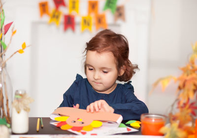 Portrait of cute girl sitting on table at home