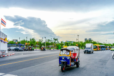 Vehicles on road against cloudy sky