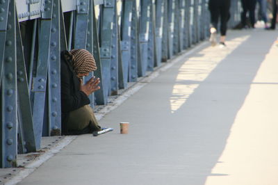 Side view of woman begging on bridge