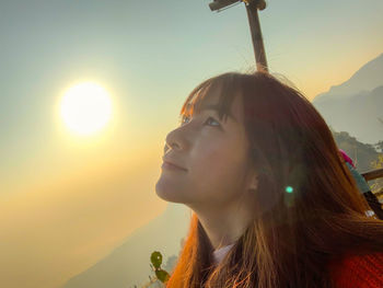 Close-up portrait of a woman looking away at sunset