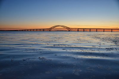 Bridge over river against sky during sunset