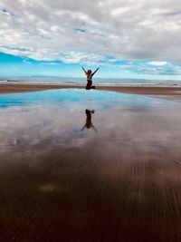 Rear view of person standing in sea against sky