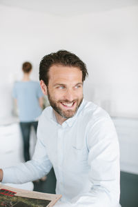 Mid adult man in office, people on background