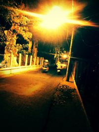 Illuminated road by building against sky