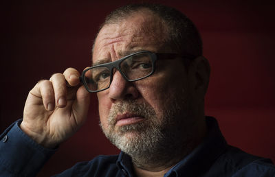Close-up portrait of man with eyeglasses against black background
