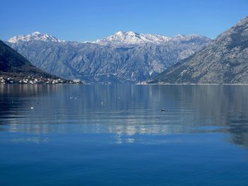 Scenic view of lake and snowcapped mountains against clear blue sky