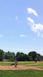 People playing soccer on field against sky