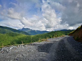 Scenic view of road by mountains against sky