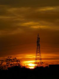 Low angle view of silhouette electricity pylon against sky during sunset