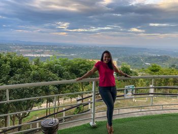 Full length of woman standing by railing against sky