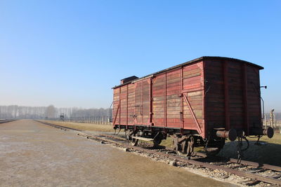 Old abandoned freight train car on track against blue sky