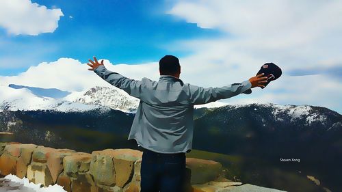 Man standing on mountain against cloudy sky